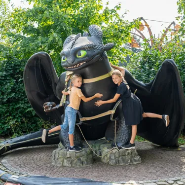 Zwei Mädchen umarmen einen großen Ohnezahn.