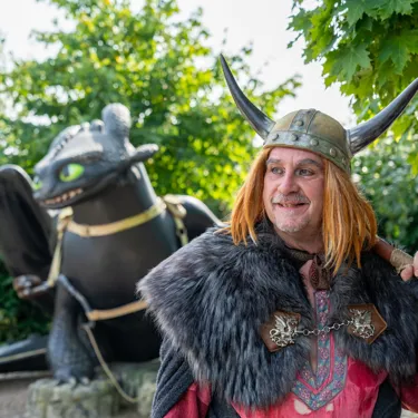 Ein Wikinger ist im Vordergrund zu sehen. Im Hintergrund ist eine große Ohnezahn-Figur zu sehen.