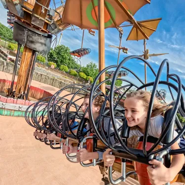 Zwei fröhliche Mädchen sind in der Attraktion "Hicks Himmelstürmer" im Heide Park Resort zu sehen.